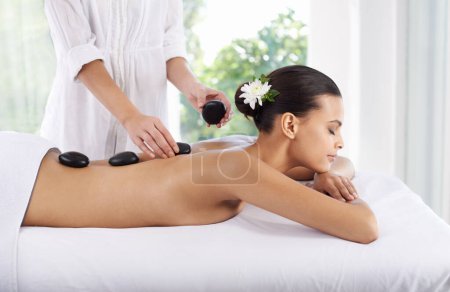 Photo for Hot stone, woman and hands massage spine for skincare, beauty and pamper body for wellness at luxury salon. Therapist, rocks and back of person at spa for treatment, relax or health with masseuse. - Royalty Free Image