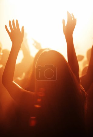 Photo for Woman, live and festival with arms raised to listen, music and dance with crowd, cheering and dancing to performance on stage. Audience, enjoy and singing with loud, sound and partying with band - Royalty Free Image