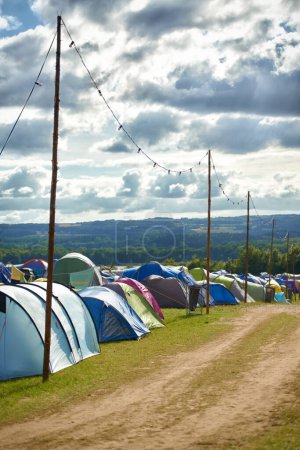 Téléchargez les photos : Camping, tentes et festival de musique en plein air dans le parc pour la célébration en vacances en été. Camping, fond ou abri lors d'une fête, d'un événement ou d'un voyage dans la nature pour un concert ou un carnaval bondé. - en image libre de droit