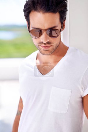 Photo for Fashion, face and man with sunglasses in living room for style, confidence and trendy eyewear for vision. Male person, cool and edgy accessory on eyes for sunlight, eyes and protection in summer. - Royalty Free Image