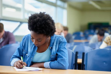 Photo for Writing, university and black woman student in classroom studying for test, exam or assignment. Education, college and female person working on project with knowledge in lecture hall for learning - Royalty Free Image