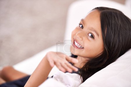 Photo for Happy, wave and portrait of child on sofa for playful, fun and rest on weekend in living room. Smile, childhood and face of young girl alone on couch for relaxing, comfortable and free time in home. - Royalty Free Image