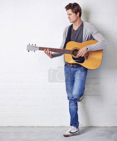 Photo for Man, guitar and musician with creativity and music, acoustic for entertainment and performance against wall background. Busker, artist and musical instrument for art, track or song with talent. - Royalty Free Image