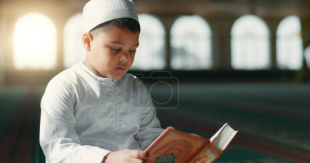 Foto de Islam, niño en la mezquita leyendo el Corán para aprender, la atención plena y la gratitud en la fe con la oración. Adoración, religión y estudiante musulmán en el templo santo alabanza con libro, enseñanza espiritual y estudio - Imagen libre de derechos