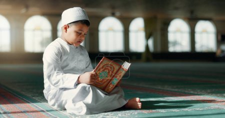 Téléchargez les photos : Islam, garçon dans la mosquée lisant le Coran pour avoir appris la pleine conscience et la gratitude dans la foi avec la prière des enfants. Culte, religion et étudiant musulman dans la louange du temple sacré avec livre, enseignement spirituel et étude. - en image libre de droit