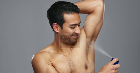 Photo for Grooming, hygiene and man spraying armpit with perfume in studio, wellness and fragrance isolated on grey background. Deodorant, beauty and cosmetic product with body care, clean and fresh with skin. - Royalty Free Image