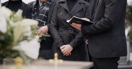 Photo for Bible, hands and family at funeral, cemetery or burial ceremony religion by coffin tomb. Holy book, death and grief of people at graveyard, Christian priest reading spiritual gospel and faith in God. - Royalty Free Image