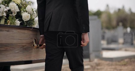 Photo for Coffin, hands and man walking at funeral ceremony outdoor with pallbearers at tomb. Death, grief and person carrying casket at cemetery, graveyard or family service of people mourning at windy event. - Royalty Free Image