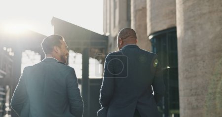 Photo for Business, men and travel in city with discussion for morning commute, partnership and rear view with lens flare. Employees, people and talking for collaboration and networking outdoor in urban town. - Royalty Free Image