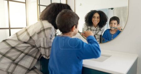 Photo for Woman, child and brushing teeth in bathroom with mirror, dental care in home with toothpaste, water and hygiene. Kid, mom and toothbrush, teaching, learning and cleaning mouth morning with reflection. - Royalty Free Image