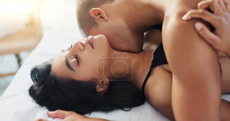 Photo for Couple, kiss in bed and sex for intimacy, people bond for relationship or passion with love and trust at home. Foreplay, lust and seduction on Valentines day with sexual moment and romance in bedroom. - Royalty Free Image