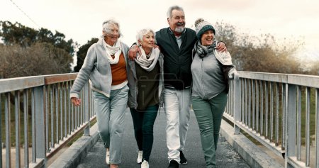 Photo for Senior people, fitness group and bridge with laugh, care or walk for training together, health or retirement. Elderly friends, hug and conversation with exercise, outdoor workout or pointing in park. - Royalty Free Image