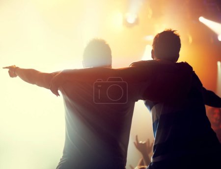 Foto de Noche, concierto y amigos bailan con música en el festival, evento de fiesta en vacaciones y vacaciones. Rock, fans y personas se abrazan en celebración en el club disco, rave y público con luz desde el escenario. - Imagen libre de derechos