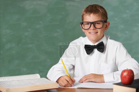 Photo for Young boy, portrait and writing at school for learning, education or knowledge with green chalk board. Face of male person, smart child or teenager smile with books for academic literature in class. - Royalty Free Image