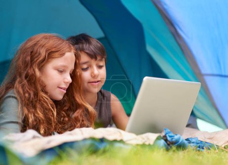 Photo for Children, family and happy with laptop in tent for camping, social media and online movie with watching in nature. Friends, face and kids with smile outdoor on grass for gaming, relax and holiday fun. - Royalty Free Image