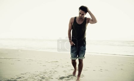 Photo for Man, beach and thinking at sunrise on holiday in trendy clothes, remember and walk in morning by waves. Person, ocean and sea with idea, outdoor and vision on island in nature, choice and decision. - Royalty Free Image