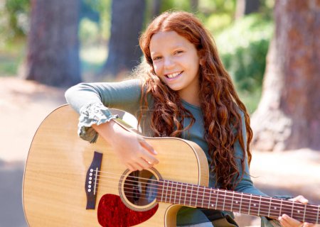 Photo for Camp, portrait and girl child with guitar for entertainment, talent or music in woods or forest. Nature, musician and kid with acoustic string instrument outdoor in park or field on weekend trip - Royalty Free Image