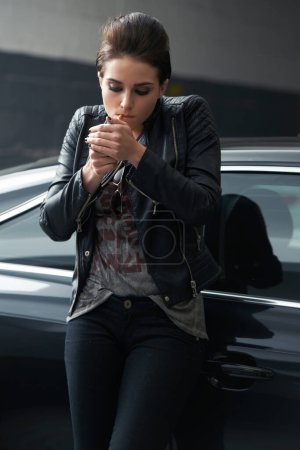 Foto de Mujer, coche y fumar cigarrillo en el estacionamiento mientras espera la recogida o el transporte. Mujer, fumadora o conductora de moda con chaqueta de cuero y tabaco de alumbrado en vehículo estacionario. - Imagen libre de derechos