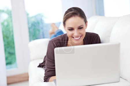 Photo for Woman, laptop and relax on sofa for remote work, streaming movies and update blog post at home. Happy freelancer, computer and download subscription, online shopping and search news on social media. - Royalty Free Image