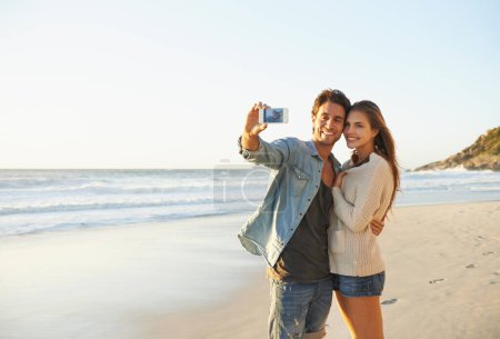 Téléchargez les photos : Couple, selfie et heureux pour étreindre par la mer pour la mémoire en vacances avec soin, amour et maquiller l'espace. Homme, femme et smartphone pour la photographie, photo de profil et application mobile à la plage sur les médias sociaux. - en image libre de droit