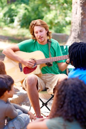 Photo for Nature, camp and man playing guitar for entertainment, talent or music in woods or forest. Singing, musician and male person with acoustic string instrument outdoor in park or field on weekend trip - Royalty Free Image