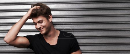 Photo for Fashion, smile and confident with man on wall background for trendy, student and youth. Happiness, tshirt and joy with face of young male person in outdoor for natural, attractive and style banner. - Royalty Free Image