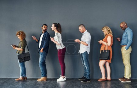 Photo for Businesspeople, waiting and queue with technology for hiring, job recruitment or onboarding. Men, women and corporate diversity in line with cellphone for staff interview, human resources or meeting. - Royalty Free Image