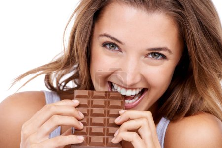 Photo for Woman, eating chocolate and portrait, candy and sweet tooth with pleasure and craving sugar on studio background. Hungry, snack and meal for comfort, dessert and sweets for calories, diet and bite. - Royalty Free Image