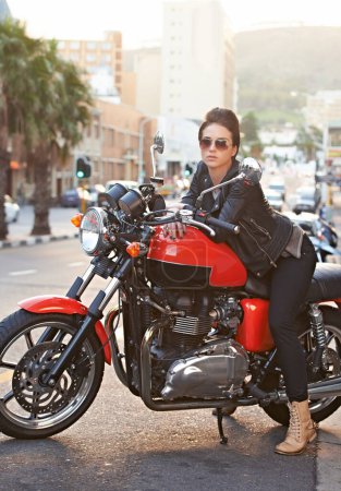 Photo for Motorcycle, leather and woman in city with sunglasses for travel, transport or road trip as rebel. Fashion, street and model with attitude on classic or vintage bike for transportation or journey. - Royalty Free Image