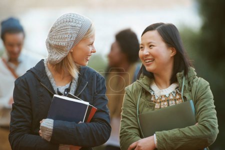 Photo for Students, women and friends outdoor on campus for university, conversation and walking to class with smile. College, communication and books for studying, education and academic growth with talk. - Royalty Free Image