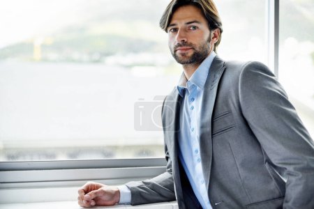 Photo for Business man, entrepreneur and serious by window in portrait, confident and professional in office. Male person, employee and pride for career at startup company, professional and expert at workplace. - Royalty Free Image