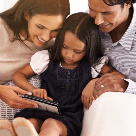 Photo for Happy parents, child and tablet for entertainment, social media or games on sofa at home. Mother, father and daughter on technology for online streaming, movie or reading ebook in elearning at house. - Royalty Free Image