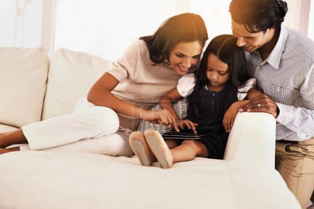 Photo for Happy parents, child and tablet on sofa for entertainment, movie or bonding together at home. Mother, father and daughter on technology in relax for online streaming, series or reading ebook at house. - Royalty Free Image
