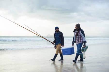 Photo for Hobby, fishing and men walking on beach together with cooler, tackle box and holiday conversation. Ocean, fisherman and friends with rods, bait and tools at waves on winter morning vacation at sea - Royalty Free Image