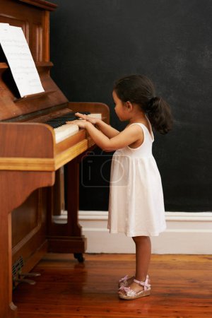 Photo for Piano, girl and toddler in home for learning, practice and classical education with musical notes. Training, melody and kid with talent, creative or hobby with instrument, child development or skill. - Royalty Free Image
