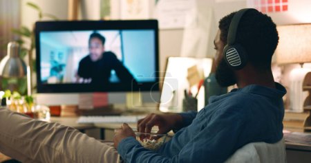 Computer, Web-Vlog und ein Mann, der im Home Office Filme mit Snacks und Essen anschaut. Entspannen Sie sich, Internet und afrikanische männliche Person mit Film-Abo-App und Tech mit Kopfhörern hören Online-Video.