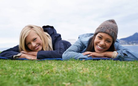 Téléchargez les photos : Pique-nique, herbe et portrait de femmes se détendre dans le champ avec le sourire, heureux et se détendre le week-end à l'extérieur. Amis, la campagne et les gens dans la prairie pour coller en vacances, vacances et aventure dans la nature. - en image libre de droit