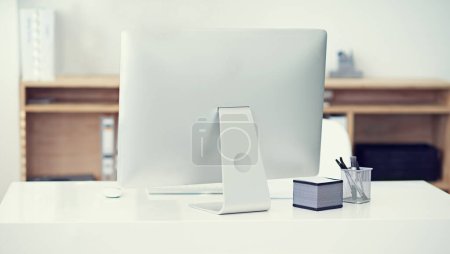 Photo for Modern, office and computer in workspace on desk with stationery, pens and sticky notes on table. Technology, furniture and back view of monitor in empty, comfortable and interior of workplace. - Royalty Free Image