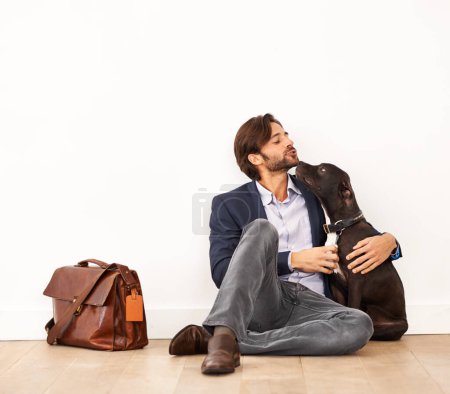 Photo for Cute, love and happy businessman with dog for bonding together with positive and good attitude. Career, briefcase and professional male person playing with pet, puppy or animal on floor at home - Royalty Free Image