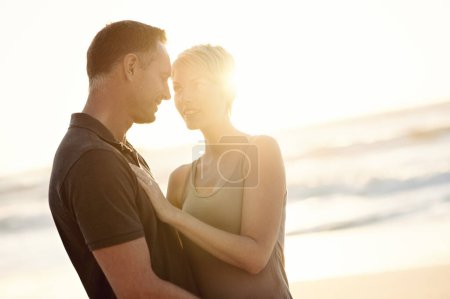 Photo for Couple, face and happy on beach with love for bonding, honeymoon date and weekend holiday with sunset. Lens flare, man and woman with embrace, smile and care for vacation, travel and adventure at sea. - Royalty Free Image