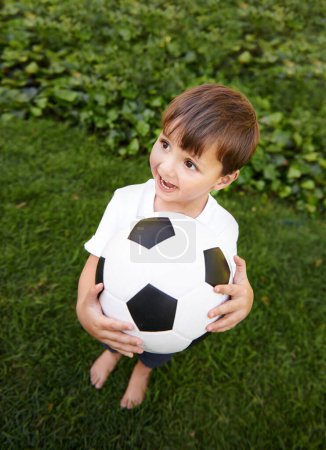 Téléchargez les photos : Football, ballon et enfant excité dans le jardin pour le jeu, jouer et s'amuser sur l'herbe à la maison. Sourire, bonheur et garçon avec le football, la croissance et le développement dans la cour arrière pour les sports pour les enfants en bonne santé - en image libre de droit