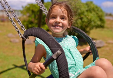 Photo for Cheerful child, swing and playing at a playground with summer hobby for kids or kindergarten leisure activity. Portrait, little girl and outdoor in nature park for fun and happiness with a smile. - Royalty Free Image