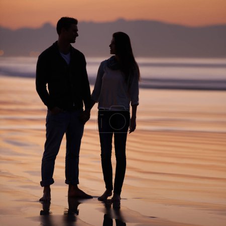 Photo for Couple, holding hands on beach and sunset, nature and travel with bonding for love and commitment outdoor. People with support, trust and loyalty with adventure together for honeymoon or anniversary. - Royalty Free Image