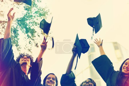 Foto de Grupo feliz, estudiantes y sombreros en celebración de la graduación, ganar o lograr en el campus. Personas o graduados lanzando gorras en el aire para el certificado, la educación o el hito en la universidad al aire libre. - Imagen libre de derechos