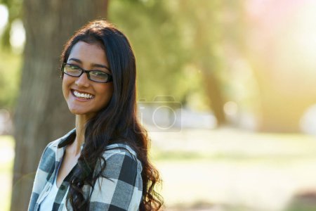 Photo for Woman, portrait and relaxing in park or garden, smiling and joyful on summer holiday. Female person, eyewear and enjoying vacation in countryside, outdoors and calm student on weekend in nature. - Royalty Free Image
