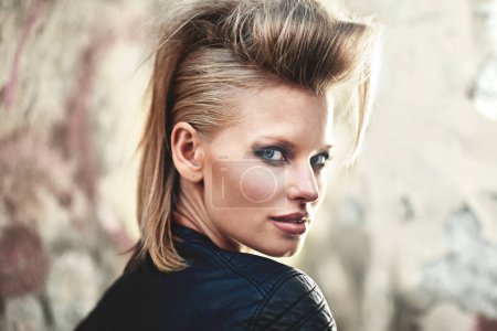 Photo for Woman, portrait and happy in edgy fashion with punk rock hairstyle, attitude and cool in funky clothes by wall. Person, face and leather jacket in urban town, unique and trendy with confidence. - Royalty Free Image