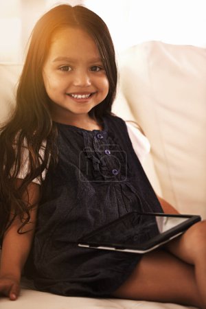Photo for Portrait, happy and little girl with tablet on sofa for entertainment, elearning or social media at home. Face of female person, child or kid with smile, technology or ebook in living room at house. - Royalty Free Image