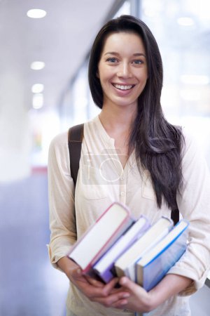Photo for Woman, portrait and smile with books in hallway for learning, scholarship and studying at university. College, student and person with face, happy and backpack for education, research and knowledge. - Royalty Free Image