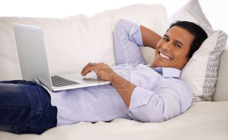 Photo for Happy man, portrait and laptop and relax on sofa for remote work, email or communication at home. Handsome businessman or freelancer with smile on computer and lying on couch in living room at house. - Royalty Free Image