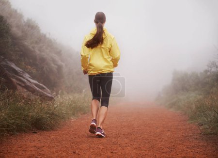 Photo for Woman, rear view and running in forest with fitness for exercise, morning routine and workout with fog and legs. Athlete, person and cardio with sportswear on outdoor trail and woods for wellness. - Royalty Free Image